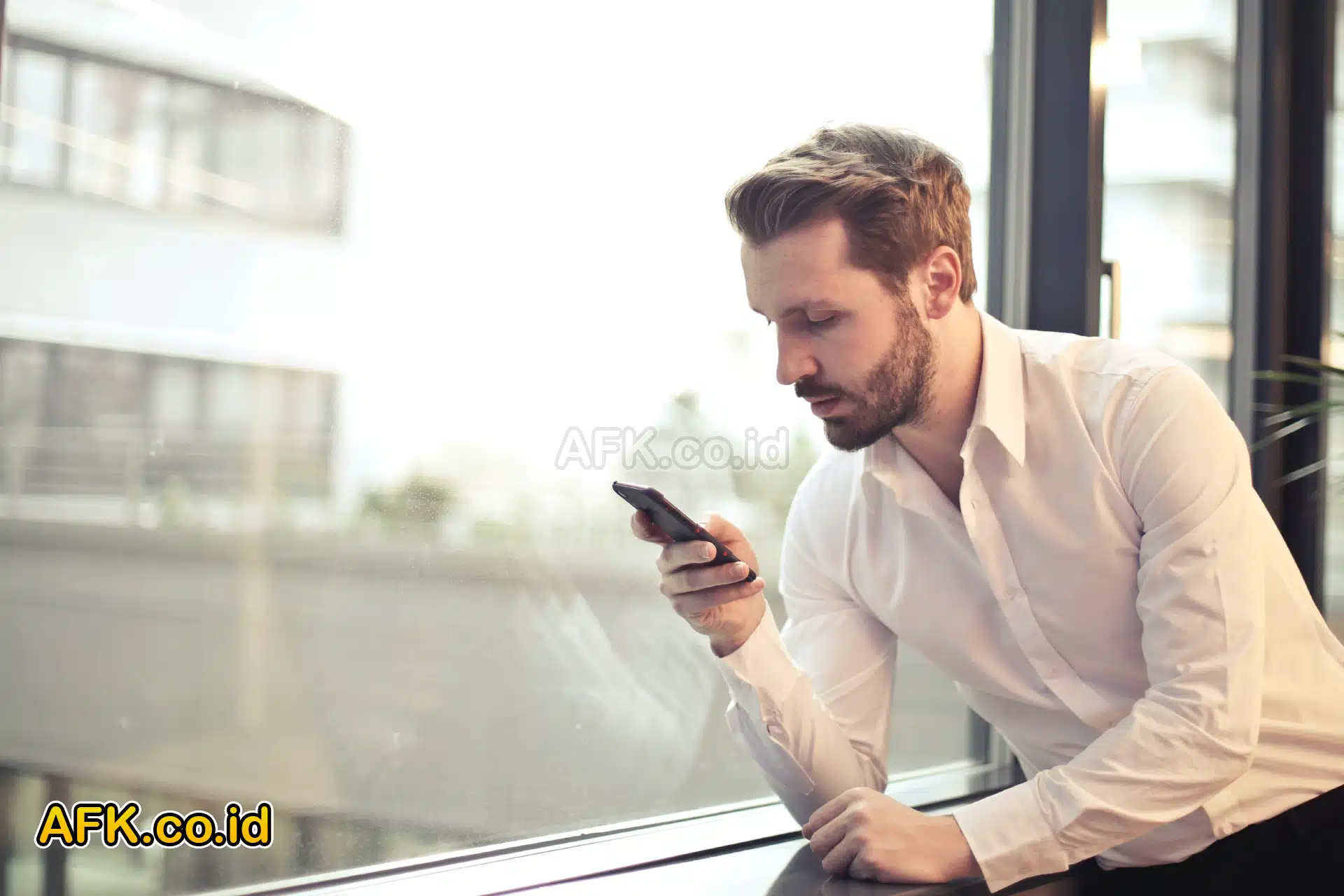 Laki-laki bermain handphone di depan kaca