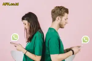 Pasangan yang duduk memunggungi, memakai baju hijau dan membuka aplikasi whatsapp