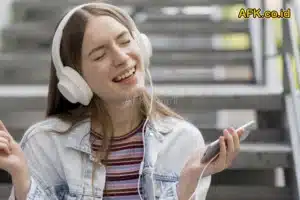 perempuan memakai headset dan mendengarkan musik di hp, duduk di tangga