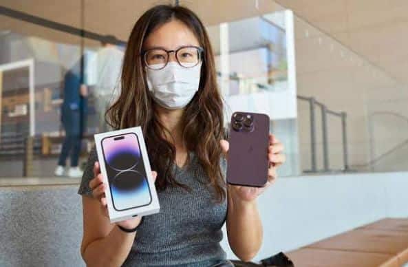 wanita memegang iphone baru di depan toko